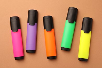 Bright color markers on pale orange background, flat lay