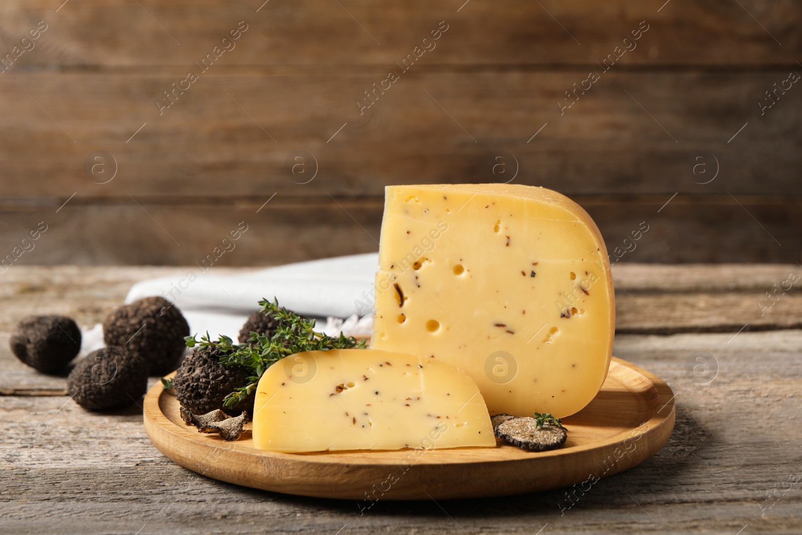 Photo of Delicious cheese, fresh black truffles and thyme on wooden table