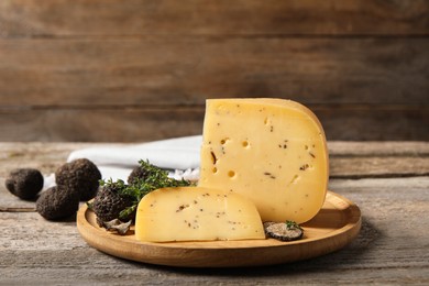 Photo of Delicious cheese, fresh black truffles and thyme on wooden table