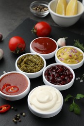 Photo of Different tasty sauces in bowls and ingredients on table