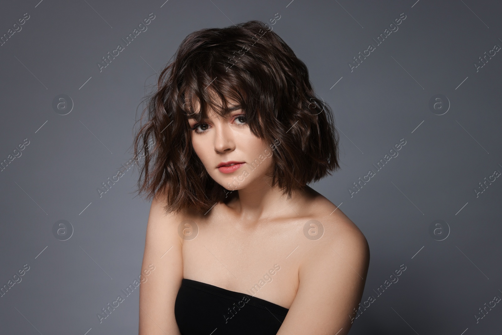 Photo of Portrait of beautiful young woman with wavy hairstyle on grey background