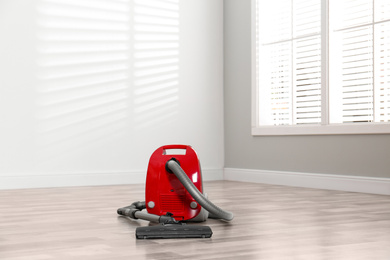 Modern red vacuum cleaner on floor indoors