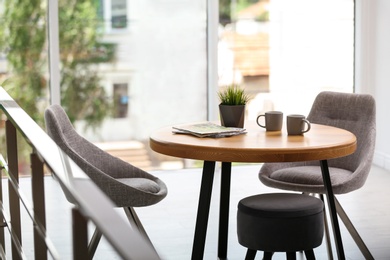 Stylish room interior with round table and comfortable chairs