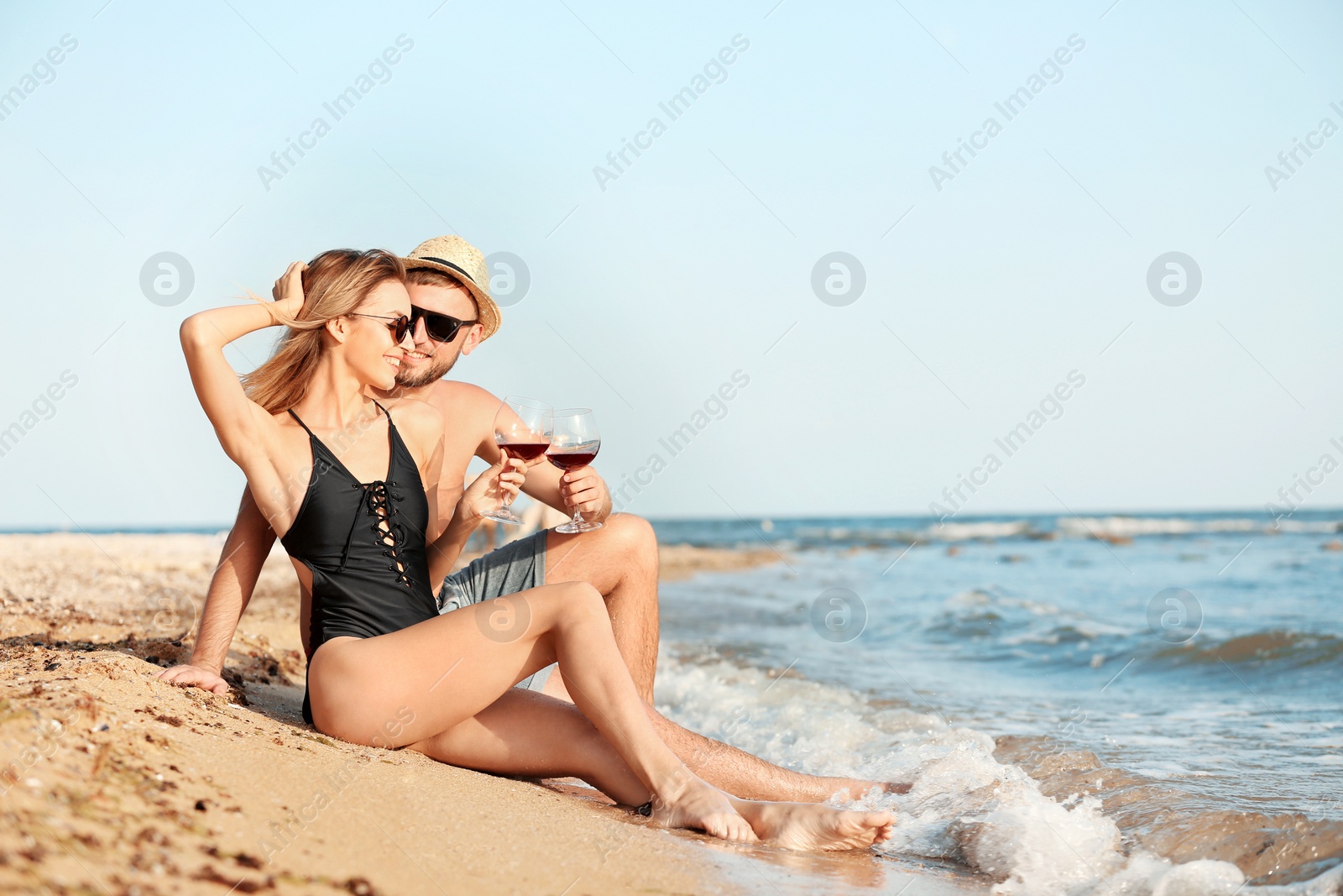 Photo of Young couple with glasses of wine on beach