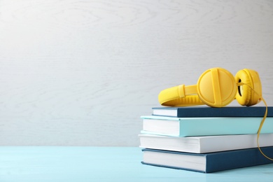 Photo of Modern headphones with hardcover book on table. Space for text