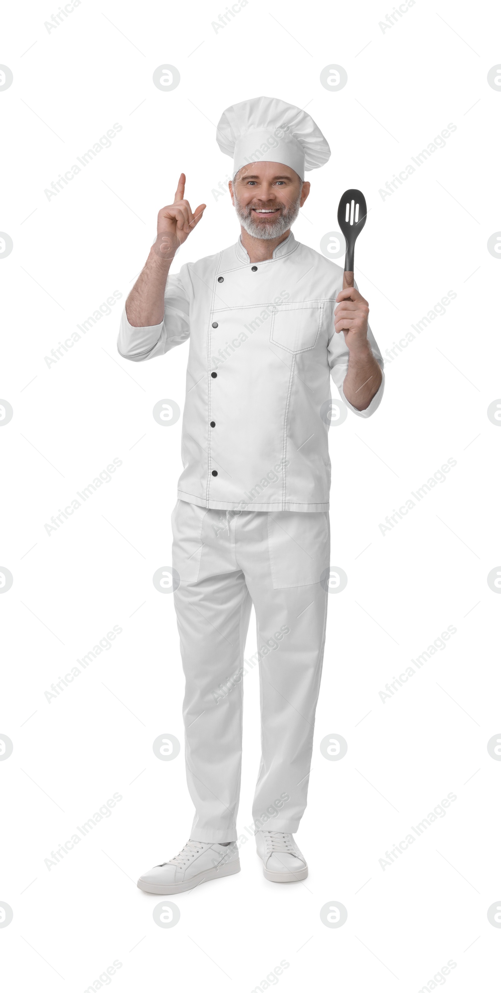 Photo of Happy chef in uniform with spoon pointing at something on white background