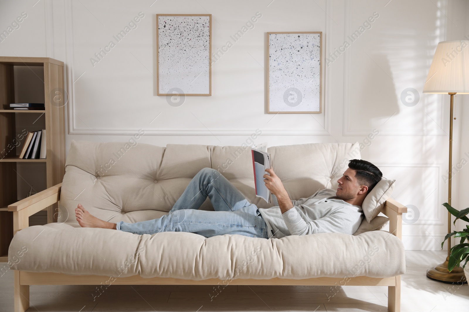 Photo of Man reading newspaper on sofa at home