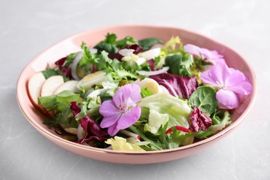 Fresh spring salad with flowers on grey table, closeup