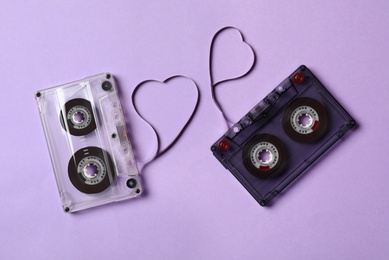 Photo of Music cassettes and hearts made of tape on violet background, flat lay. Listening love songs