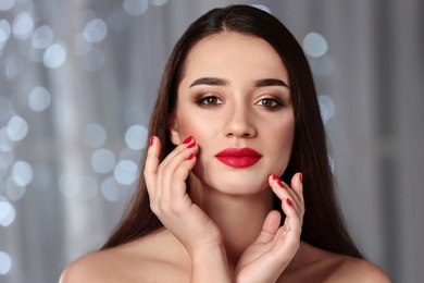 Beautiful woman with stylish nail polish against blurred lights