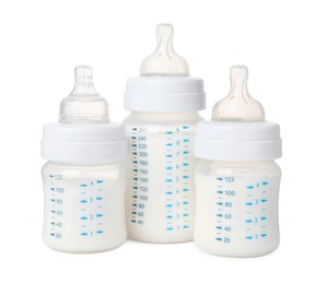 Three feeding bottles with milk on white background
