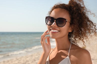 Photo of Beautiful African American woman with sun protection cream on nose at beach