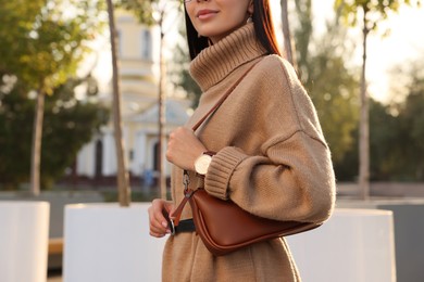 Photo of Fashionable young woman with stylish bag on city street, closeup