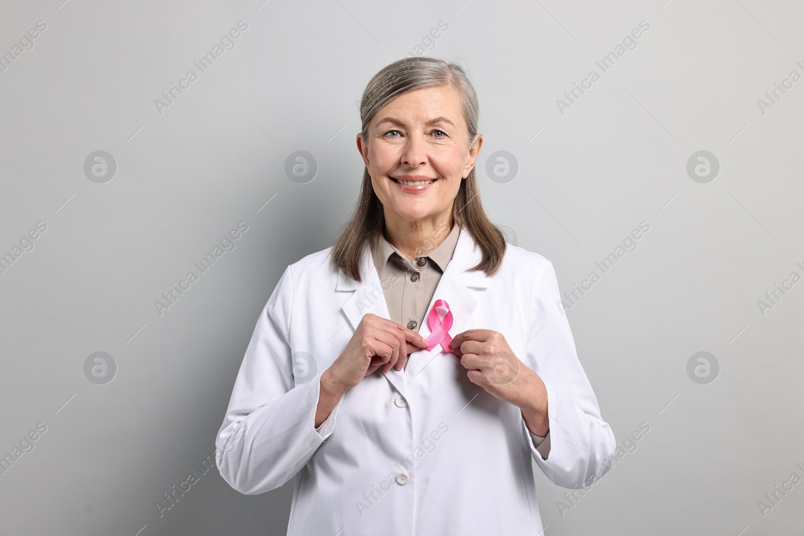 Photo of Mammologist with pink ribbon on gray background. Breast cancer awareness