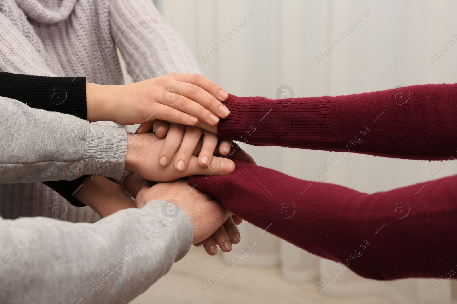 Photo of Young people putting their hands together on blurred background, closeup