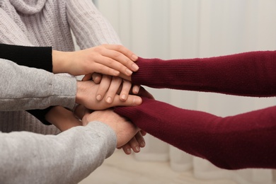 Photo of Young people putting their hands together on blurred background, closeup