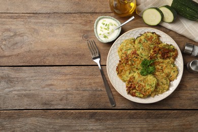 Photo of Delicious zucchini fritters served on wooden table, flat lay. Space for text