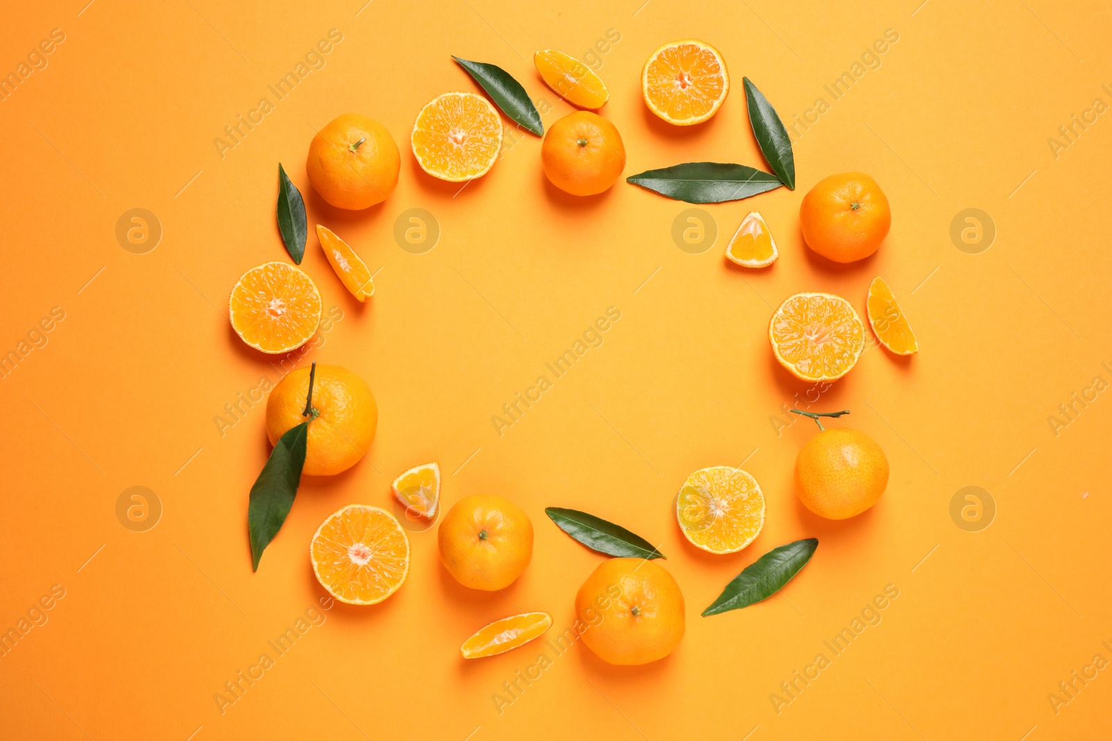 Photo of Frame made of fresh ripe tangerines and space for text on orange background, flat lay. Citrus fruit