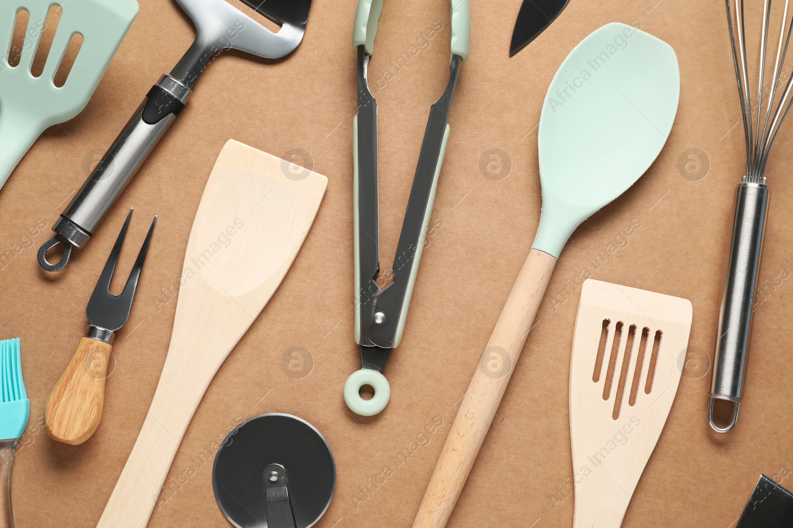 Photo of Different spatulas and other kitchen utensils on brown background, flat lay