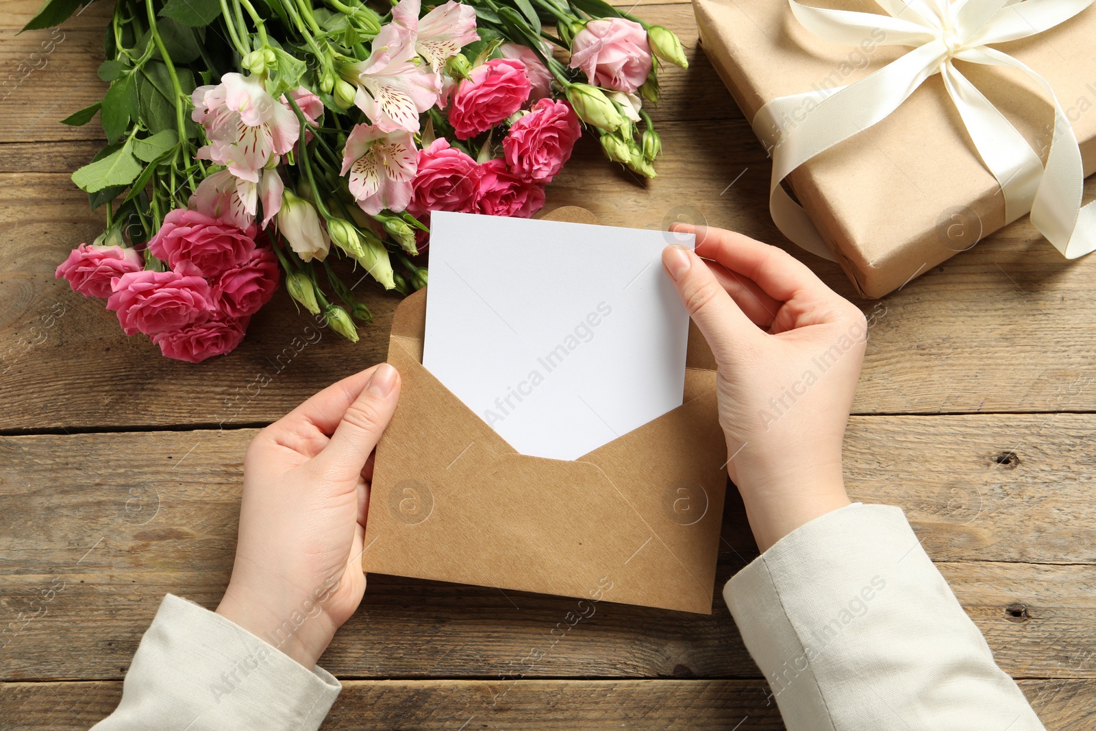 Photo of Happy Mother's Day. Woman holding envelope with blank card at wooden table, top view