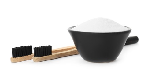 Bamboo toothbrushes and bowl with baking soda on white background