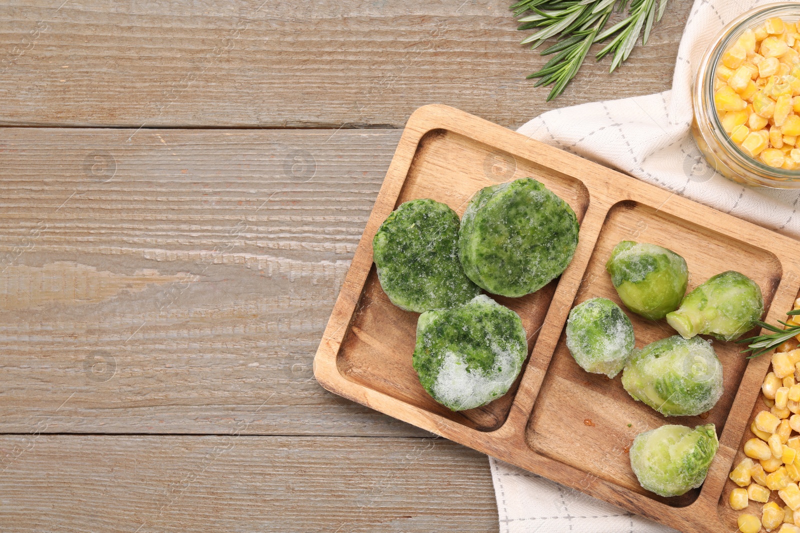 Photo of Tray with different frozen vegetables on wooden table, top view. Space for text