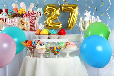 Photo of Dessert table in room decorated with golden balloons for 27 year birthday party
