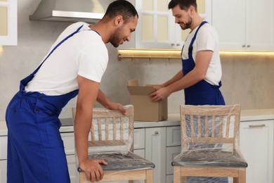 Male movers with chairs in new house