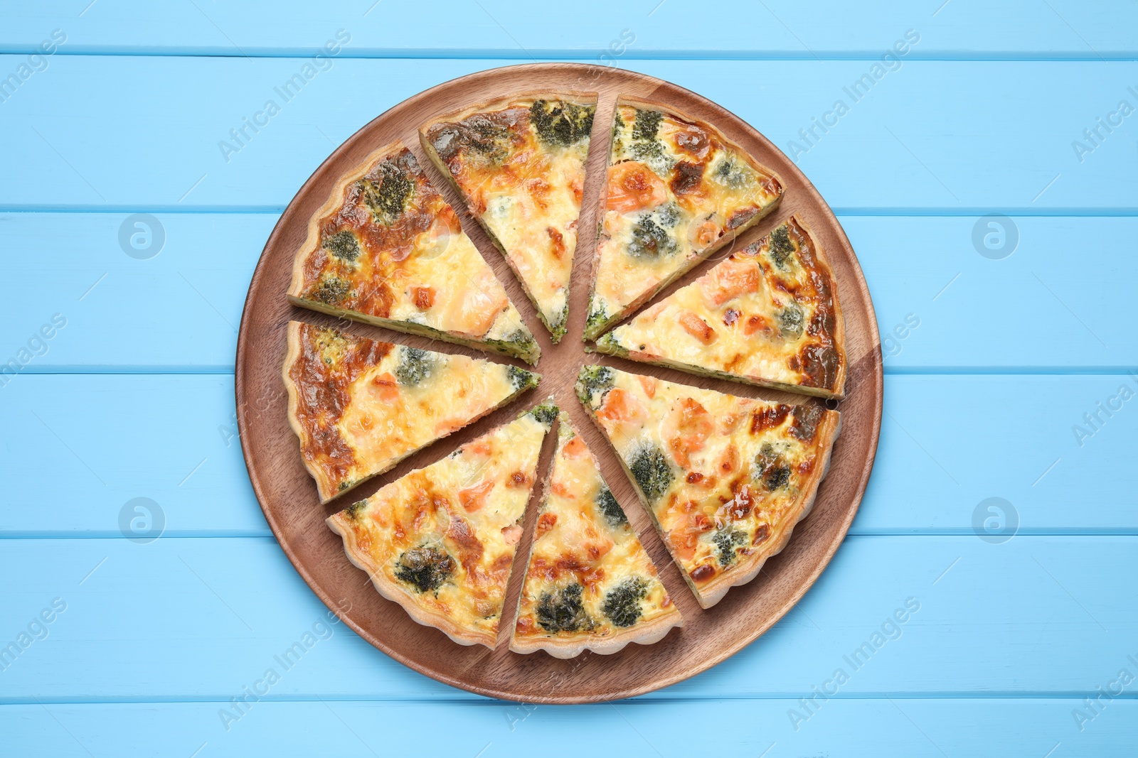 Photo of Delicious homemade quiche with salmon and broccoli on light blue wooden table, top view