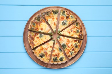 Photo of Delicious homemade quiche with salmon and broccoli on light blue wooden table, top view