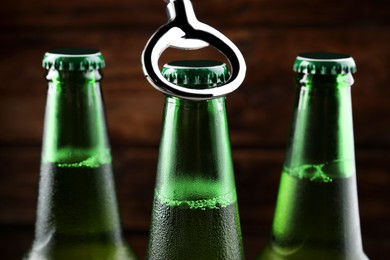 Opening bottle of beer on wooden background, closeup