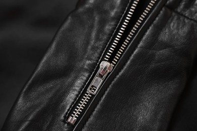 Texture of black leather jacket with zipper as background, top view