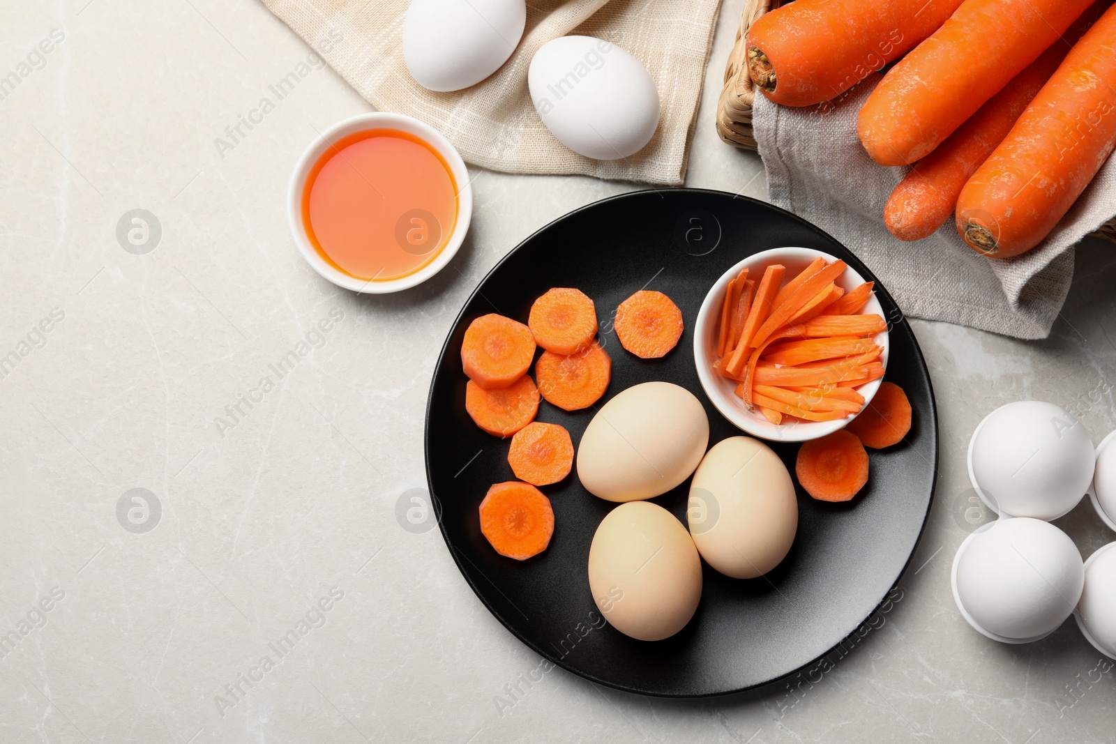Photo of Naturally painted Easter eggs on light grey table, flat lay with space for text. Carrot used for coloring