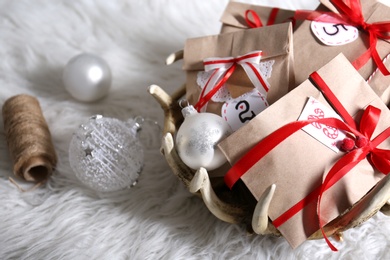 Photo of Christmas gifts and festive decor on white fluffy rug. Creating Advent calendar