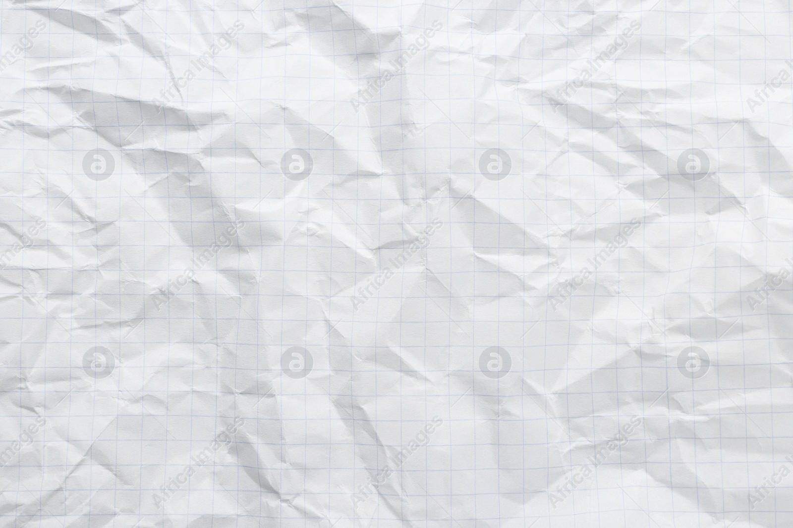 Photo of Crumpled checkered notebook sheet as background, top view