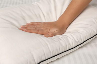 Photo of Woman touching soft pillow on bed, closeup