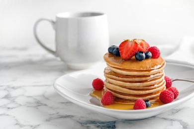 Tasty pancakes with berries and honey on plate