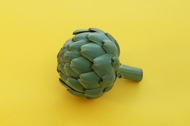 Photo of Whole fresh raw artichoke on yellow background, closeup