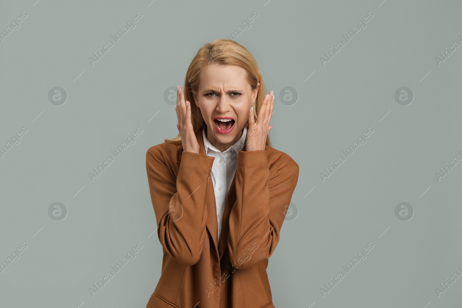 Photo of Angry young woman on grey background. Hate concept