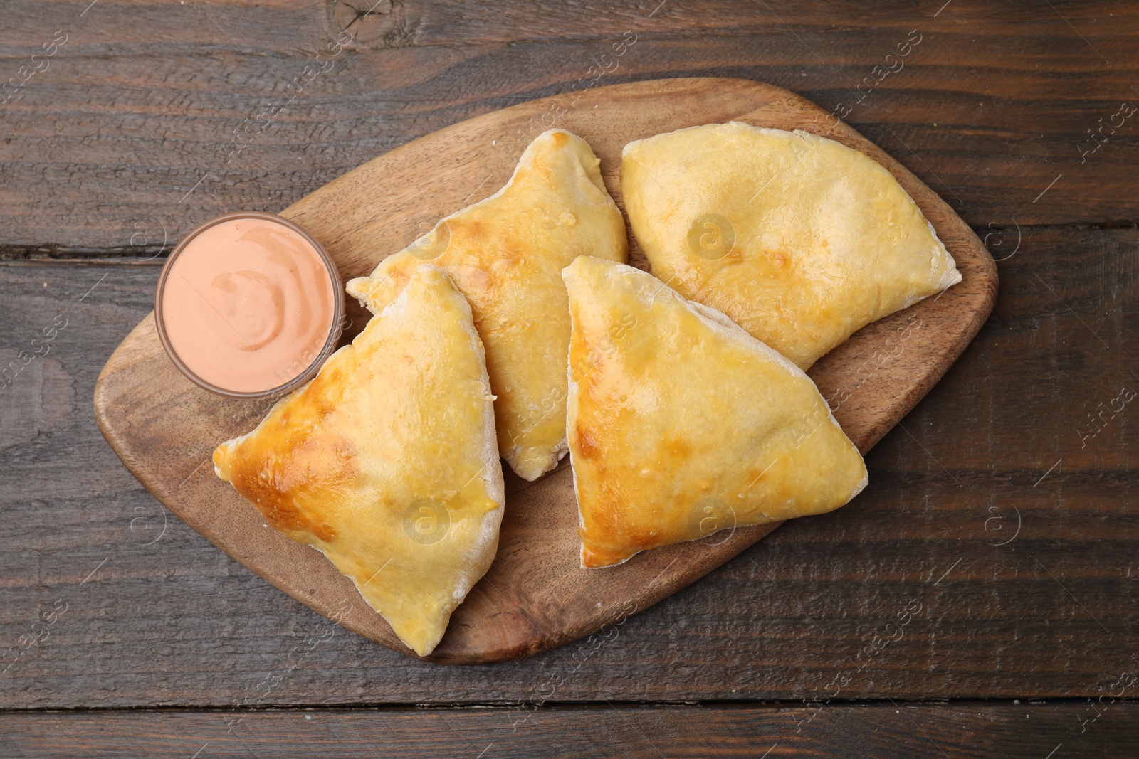 Photo of Delicious samosas and sauce on wooden table, top view