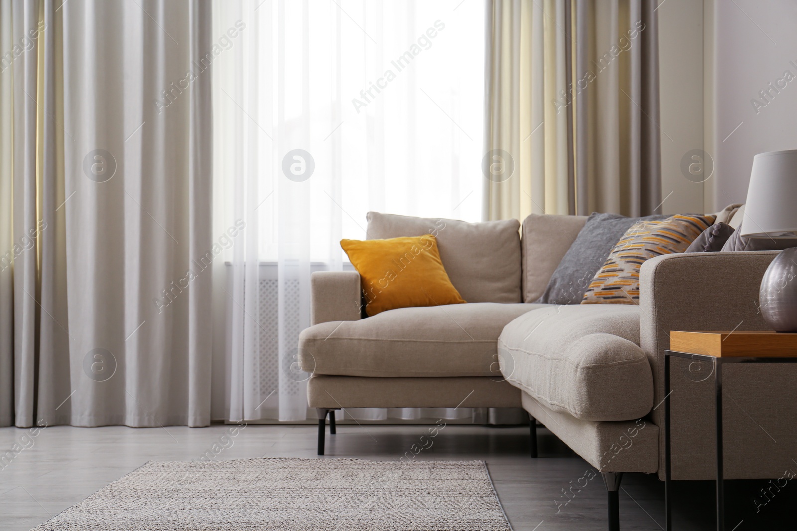 Photo of Modern comfortable sofa near window in stylish living room. Interior design