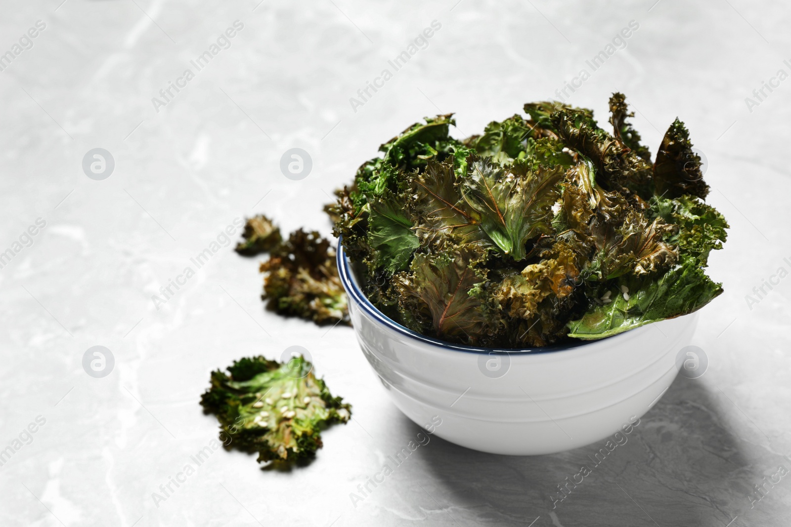 Photo of Tasty kale chips with seeds on grey marble table. Space for text