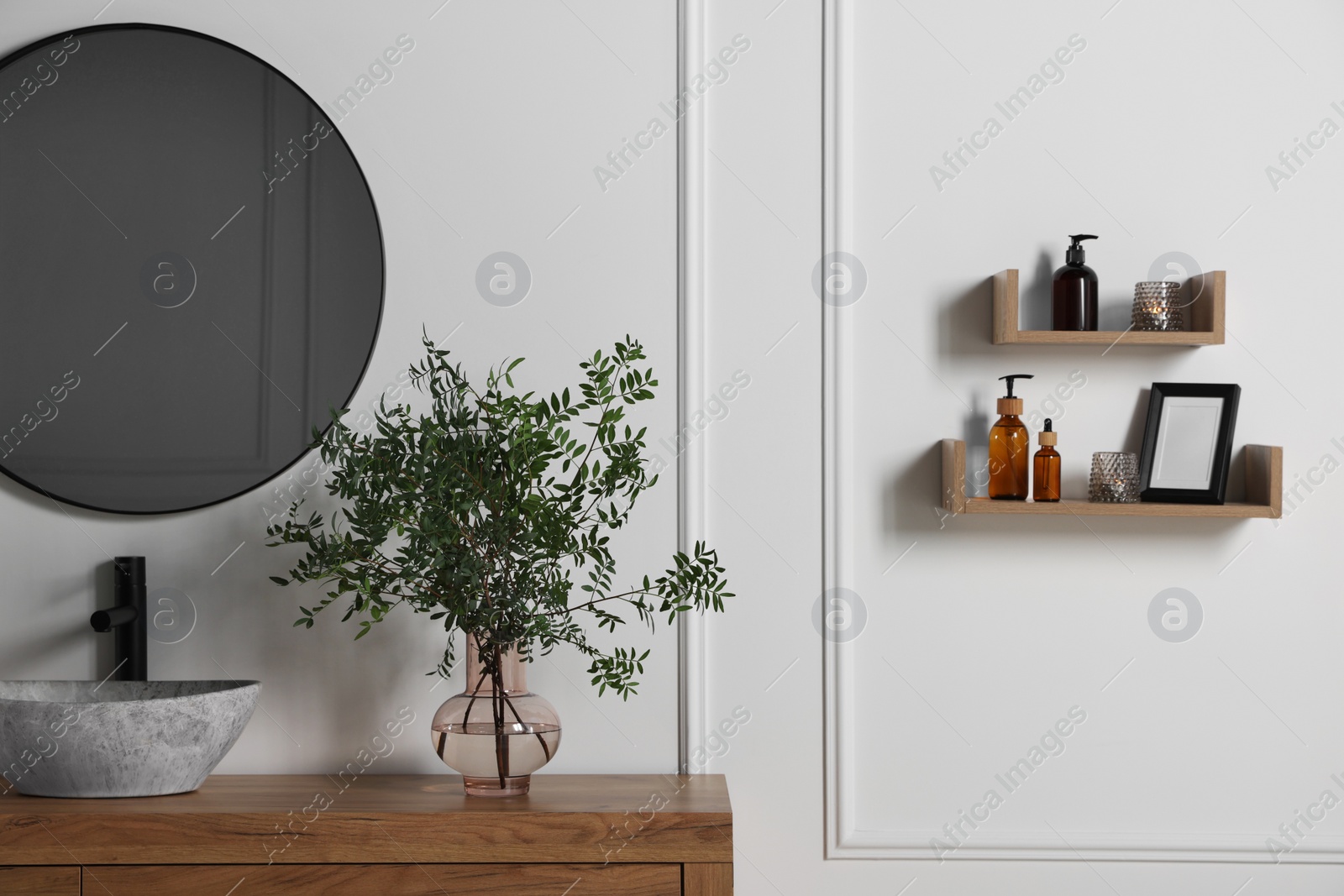 Photo of Eucalyptus branches near stylish vessel sink on bathroom vanity. Interior design