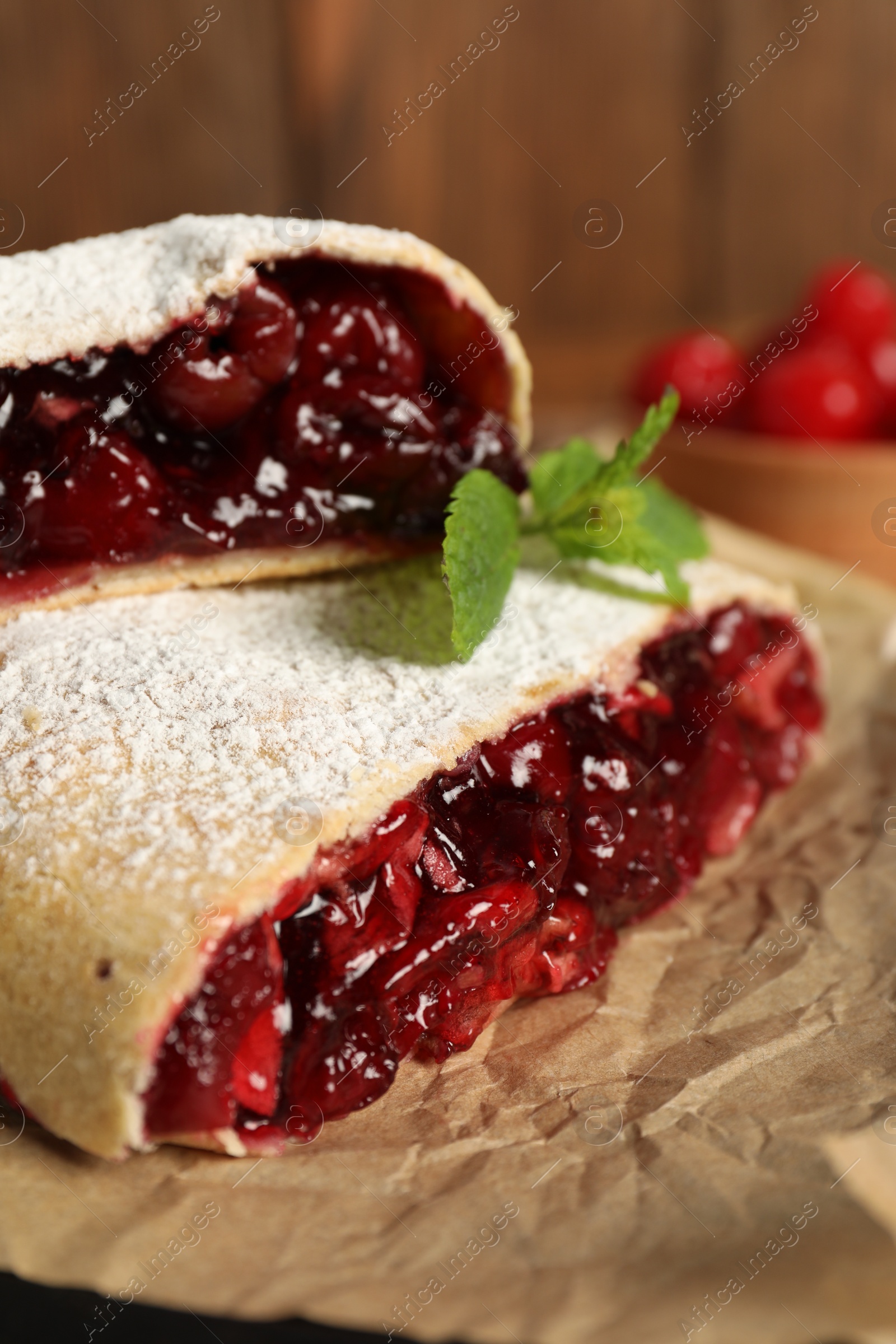 Photo of Delicious strudel with cherries on parchment, closeup