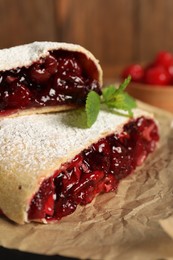 Photo of Delicious strudel with cherries on parchment, closeup