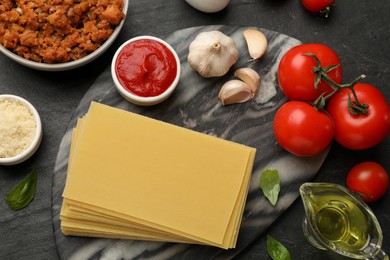 Photo of Flat lay composition with products for cooking lasagna on dark textured table