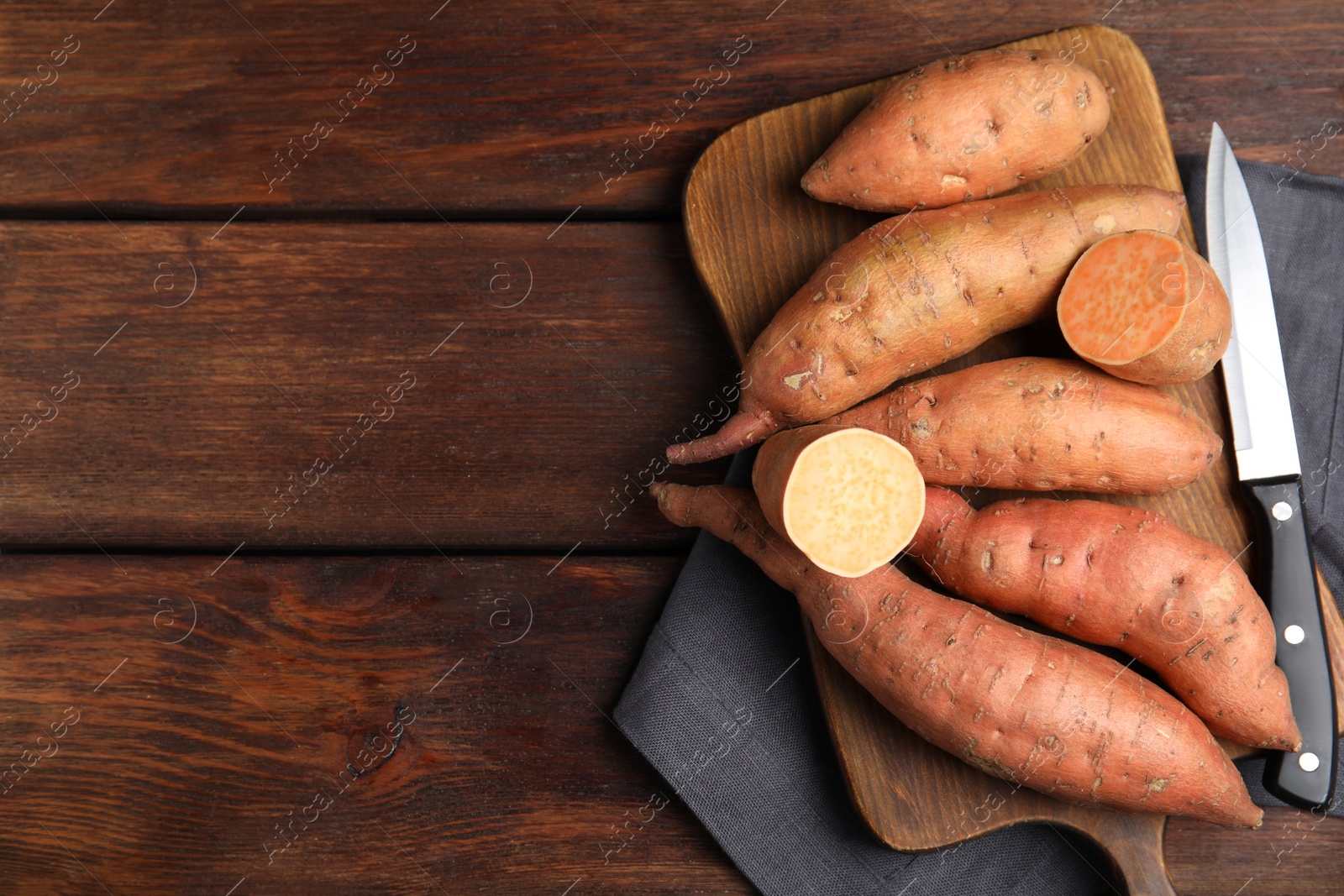 Photo of Whole and cut ripe sweet potatoes on wooden table, flat lay. Space for text