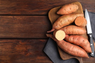 Photo of Whole and cut ripe sweet potatoes on wooden table, flat lay. Space for text