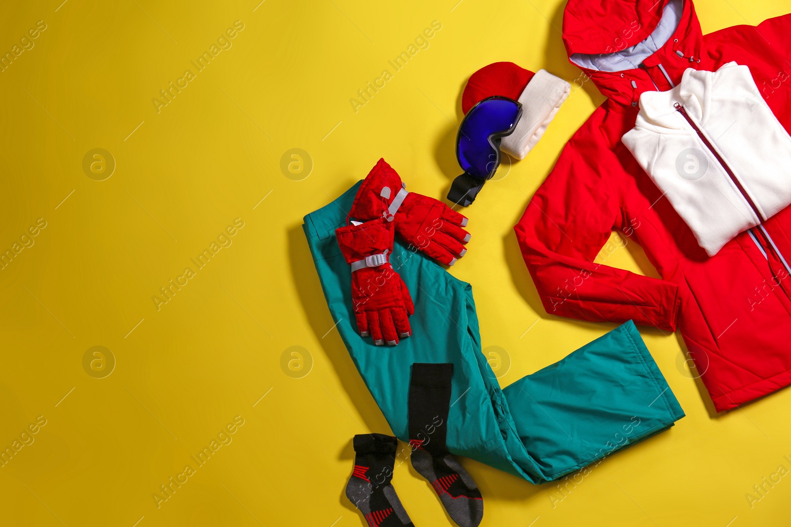 Photo of Stylish winter sport clothes on yellow background, flat lay