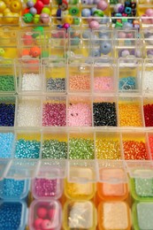 Organizers with variety of colorful beads on yellow background, closeup